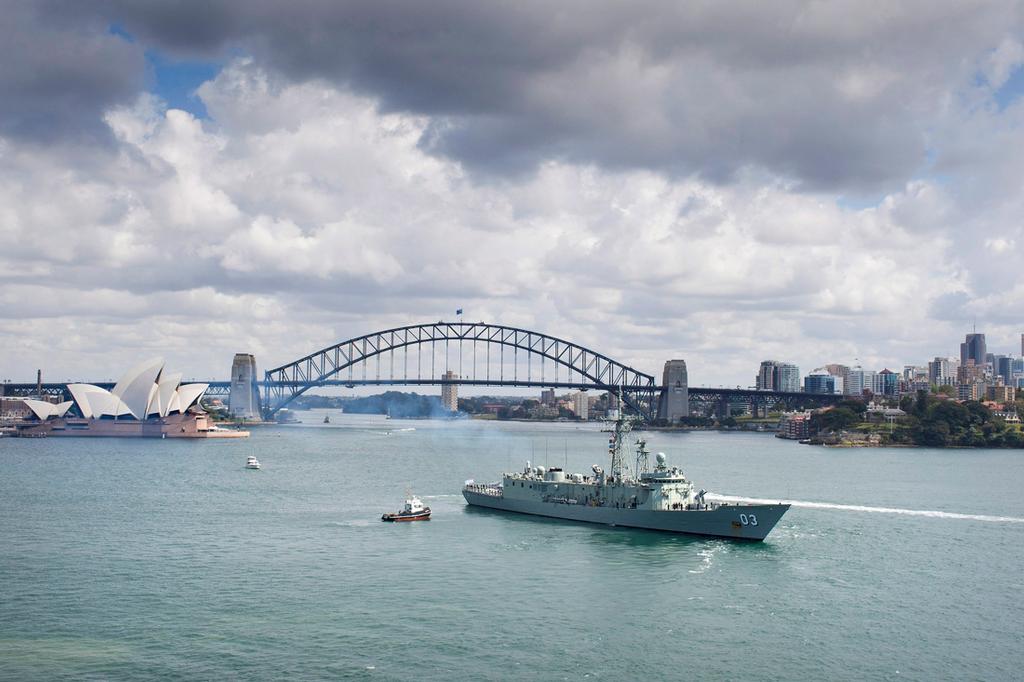 HMAS Sydney sails past the Opera House and Harbour Bridge. © SW